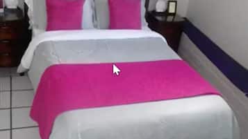 Una habitación de hotel con una cama, dos mesitas de noche y un cabecero.