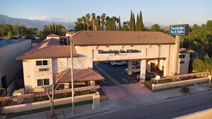 Ein Travelodge Inn & Suites mit einem Ziegeldach, Parkplatz und Blick auf die Berge im Hintergrund.