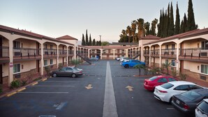 Ein mehrstöckiges Motel mit Innenhof, Parkplatz und einer Reihe geparkter Autos.