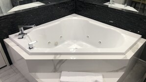 Ein modernes Badezimmer mit einer großzügigen, freistehenden Badewanne, einer Marmorarbeitsplatte und einer schwarzen, gefliesten Rückwand.