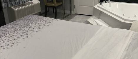 Habitación de hotel con cama, escritorio, silla, radiador y bañera.