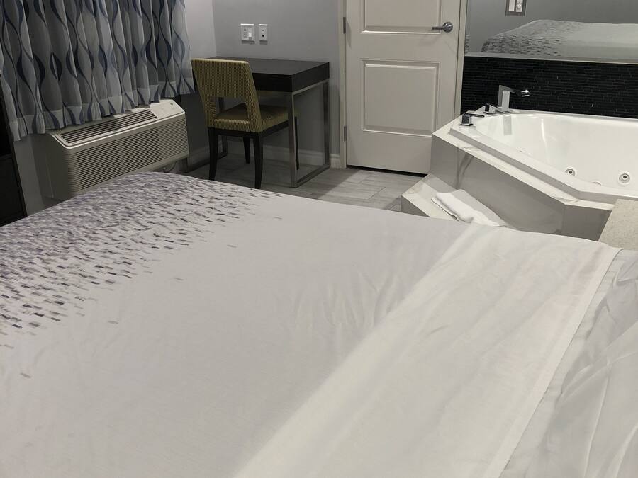 Habitación de hotel con cama, escritorio, silla, radiador y bañera.