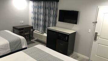 Habitación de hotel con dos camas, un escritorio, televisor y minibar.