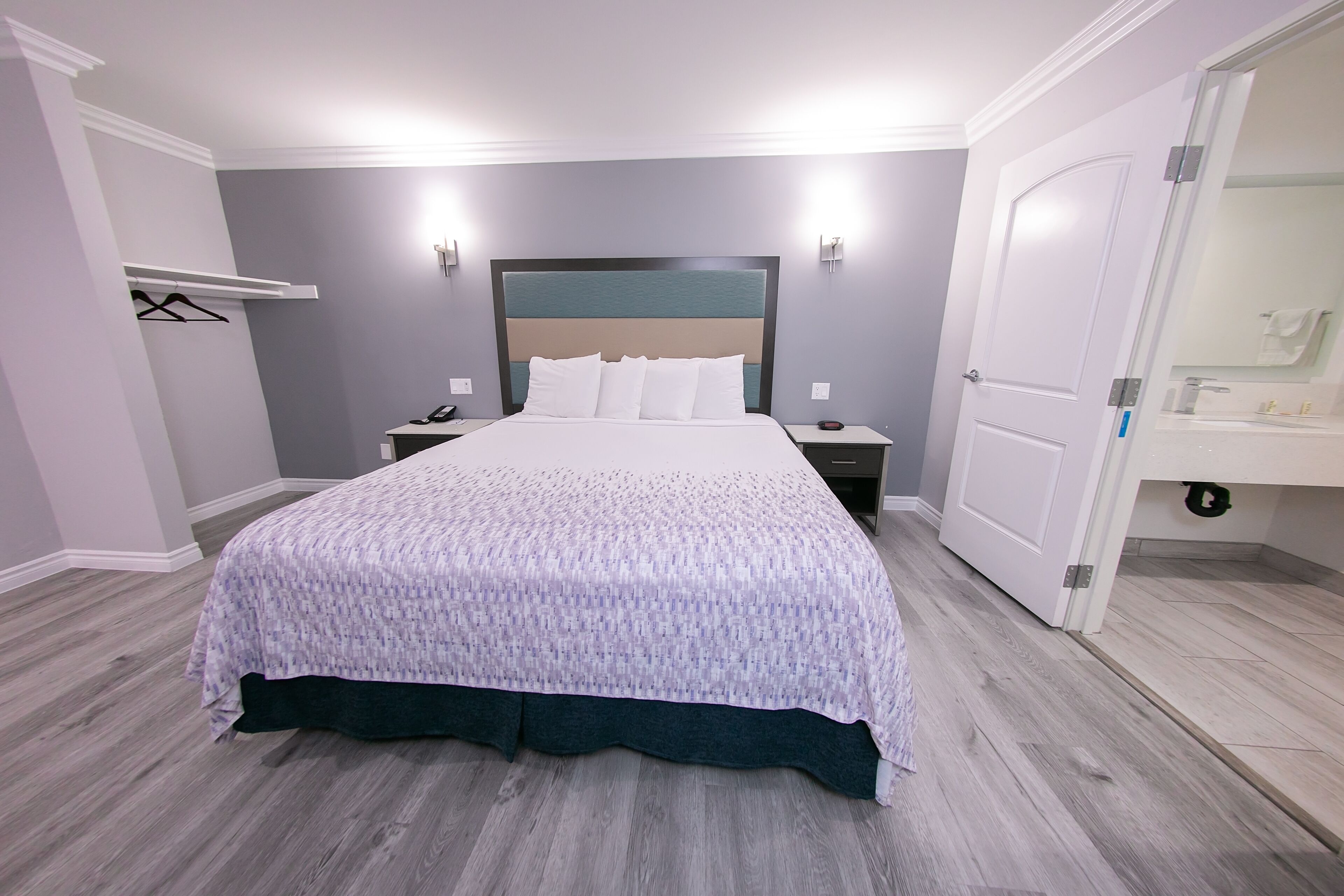 A neatly arranged bedroom with a large bed, bedside tables, a wardrobe, and a bathroom visible through an open door.