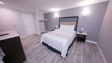 Quarto moderno com cama grande, mesas de cabeceira, guarda-roupa e porta.