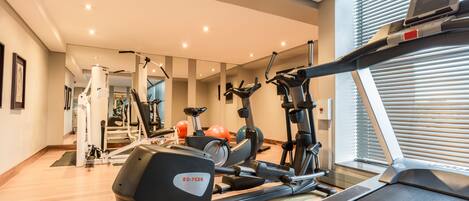 Un gimnasio con máquinas de cardio, una cinta de correr y pelotas de ejercicio.