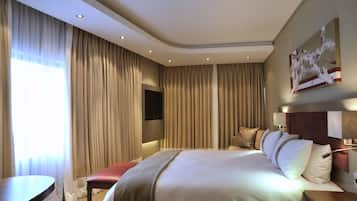 A hotel room with a large bed, a desk, and a TV mounted on the wall.