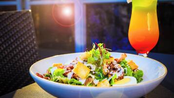 Un plato de comida con ensalada, una bebida y una silla.