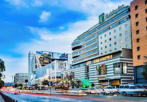 A Holiday Inn hotel with a modern design, featuring multiple floors and a prominent curved structure.