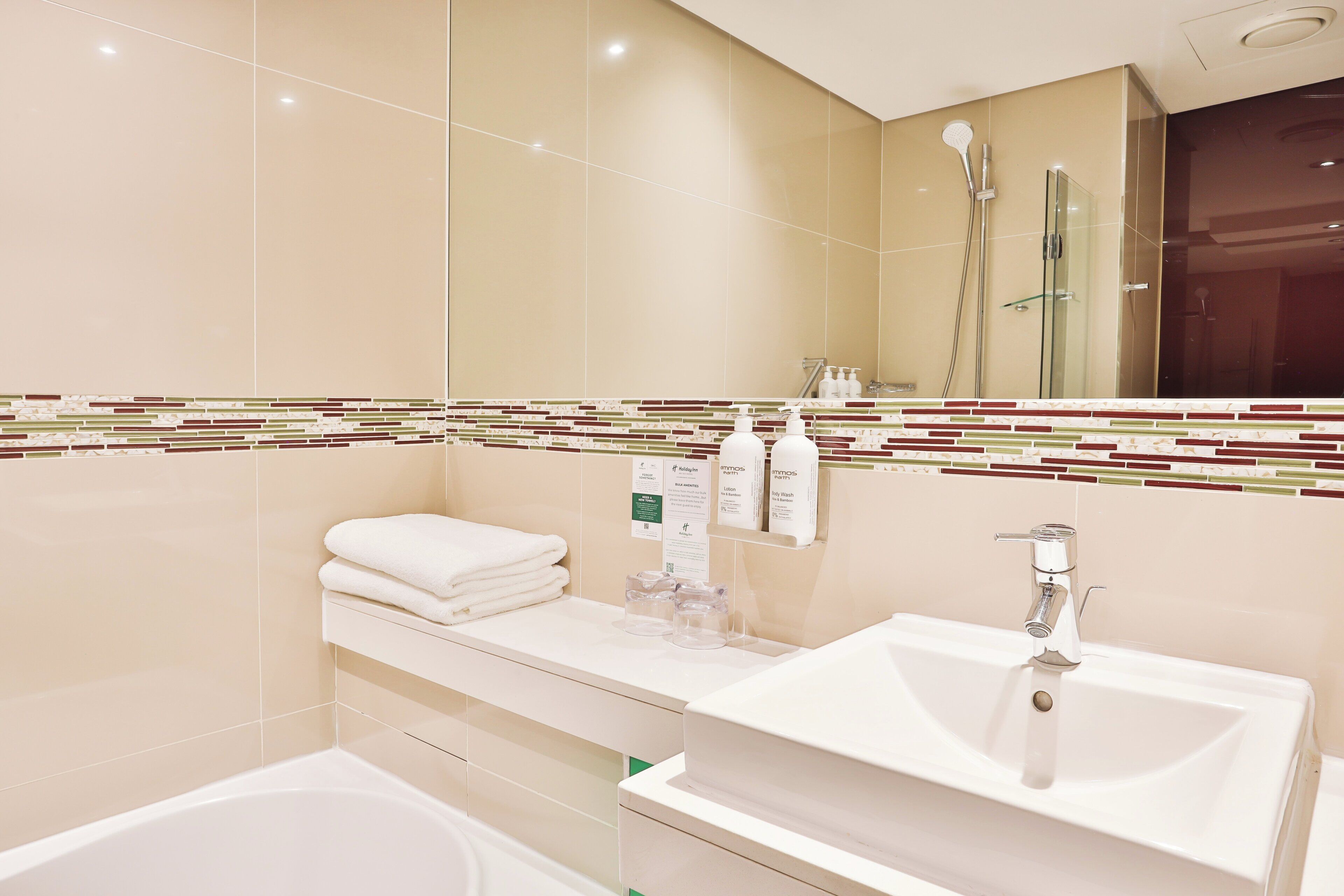 A modern bathroom with a large mirror, a sink, a shower, and a bathtub.