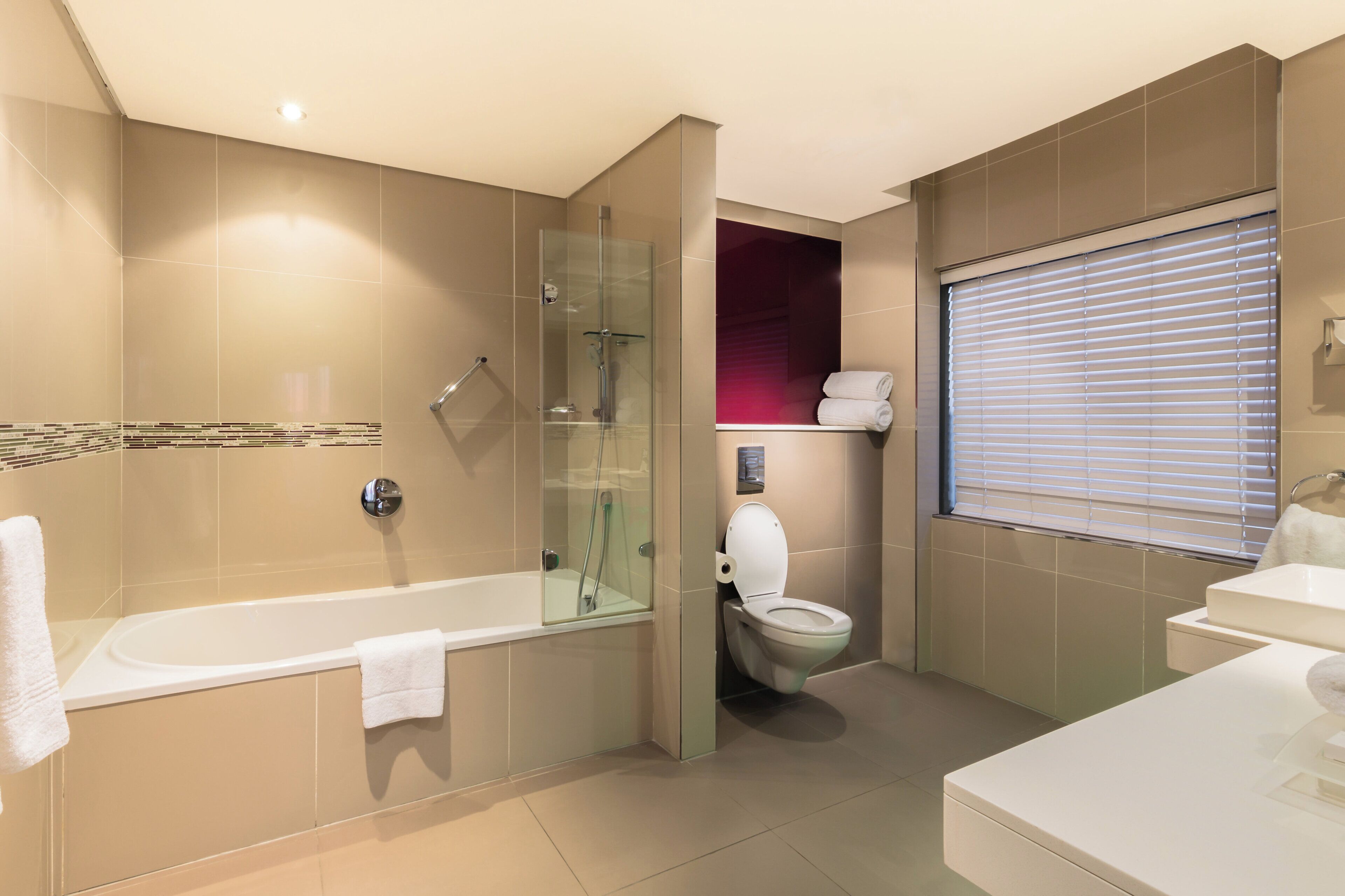 A modern bathroom with a glass-enclosed shower, a standalone toilet, and a bathtub.