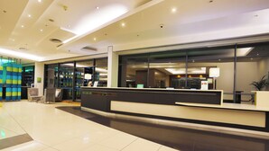 A modern hotel reception area with a reception desk, seating area, and large windows. - Holiday Inn Johannesburg - Rosebank by IHG (Johannesburg)