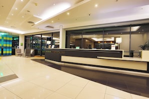 A modern hotel reception area with a reception desk, seating area, and large windows. - Holiday Inn Johannesburg - Rosebank by IHG (Johannesburg)