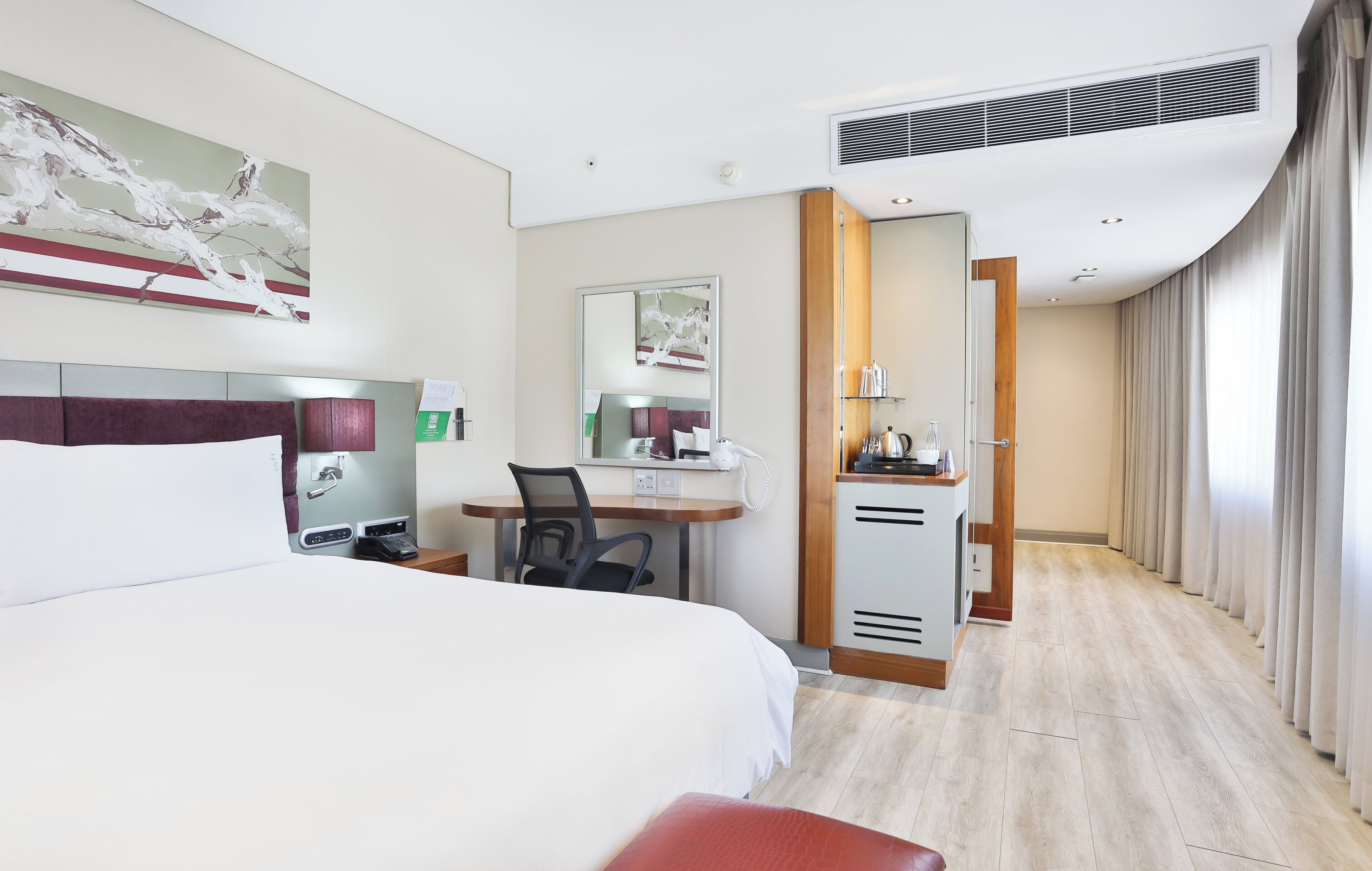 Habitación de hotel con cama, escritorio, silla y kitchenette.