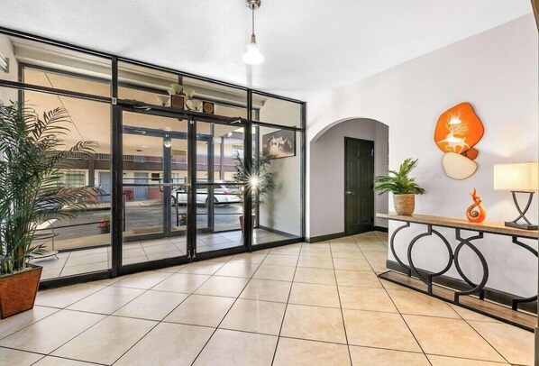 Eine Hotellobby mit Glastür, einer Rezeption und einem Blumentopf.