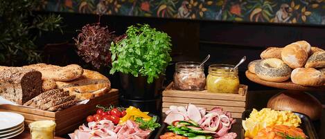 Una mesa de buffet con diversos alimentos, como panes, carnes, quesos y verduras.