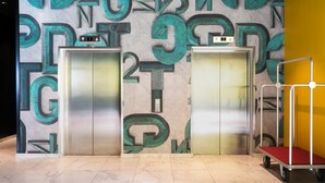 Two elevators with a wall featuring large, abstract letters. - Thon Hotel Alta (Alta)