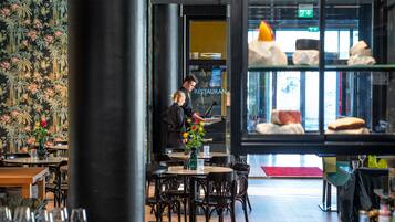 En restauranginteriör med bord, stolar och utsikt över gatan genom ett fönster.