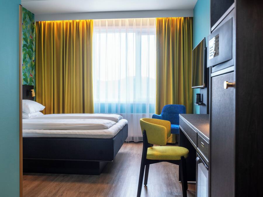 Une chambre d’hôtel comprenant un lit, un bureau avec une chaise, une télévision et une armoire.