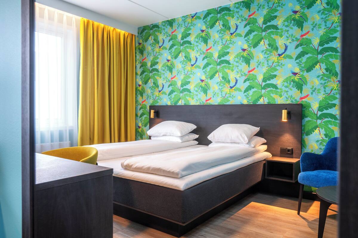 A hotel room with a bed, a desk, a chair, and a nightstand.