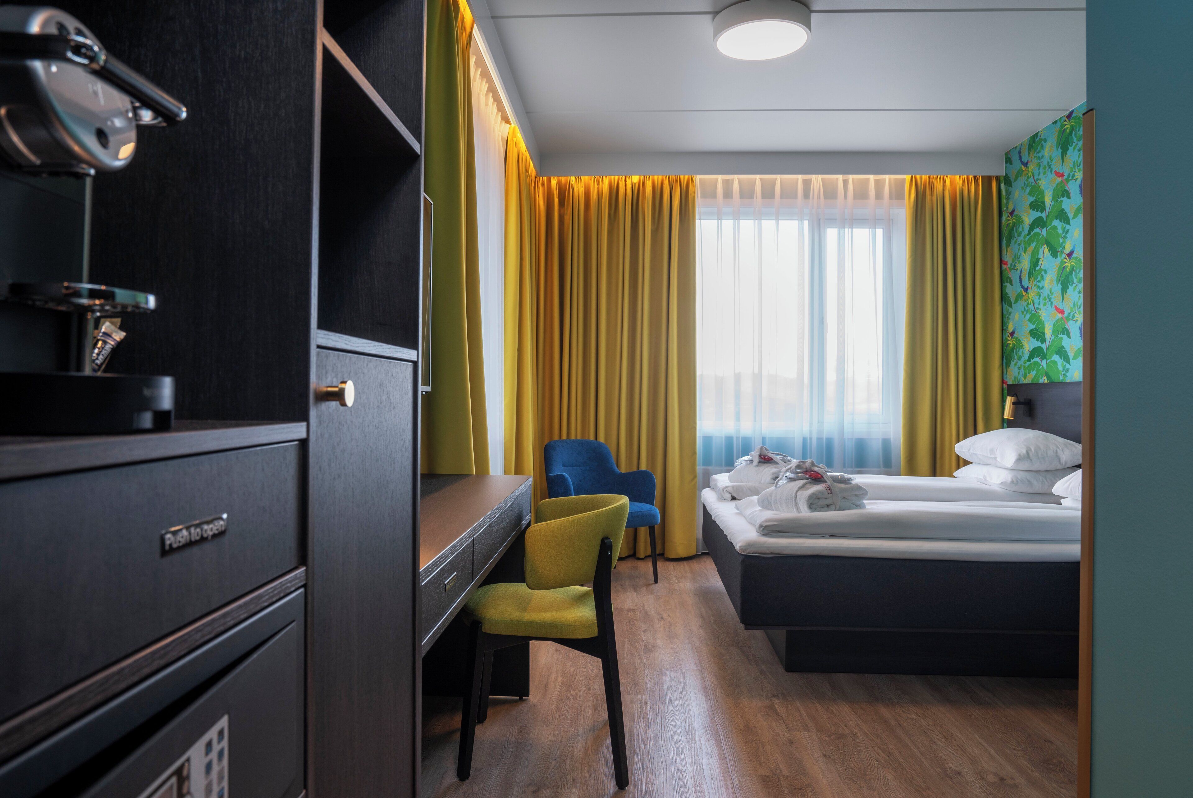 Een hotelkamer met een bed, een bureau, een stoel en een raam met gordijnen.