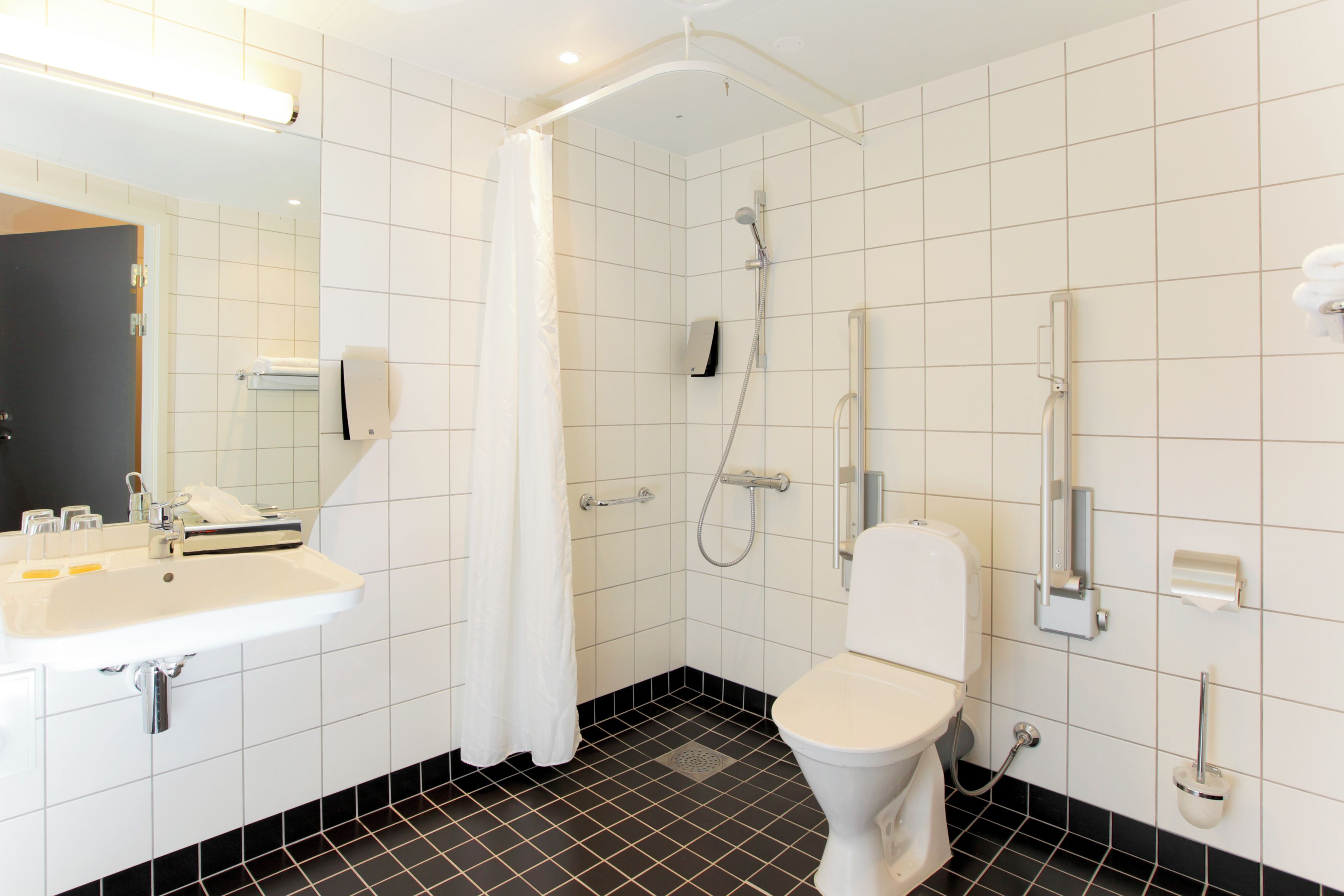 Un baño moderno con lavamanos, inodoro y ducha blancos.