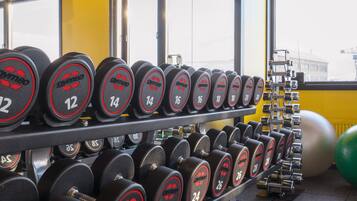 Un gimnasio con filas de mancuernas que indican el peso.