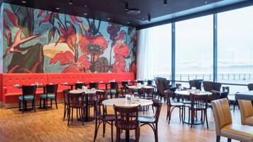 A restaurant with a vibrant floral mural, red seating, and a view of a snowy landscape through large windows.