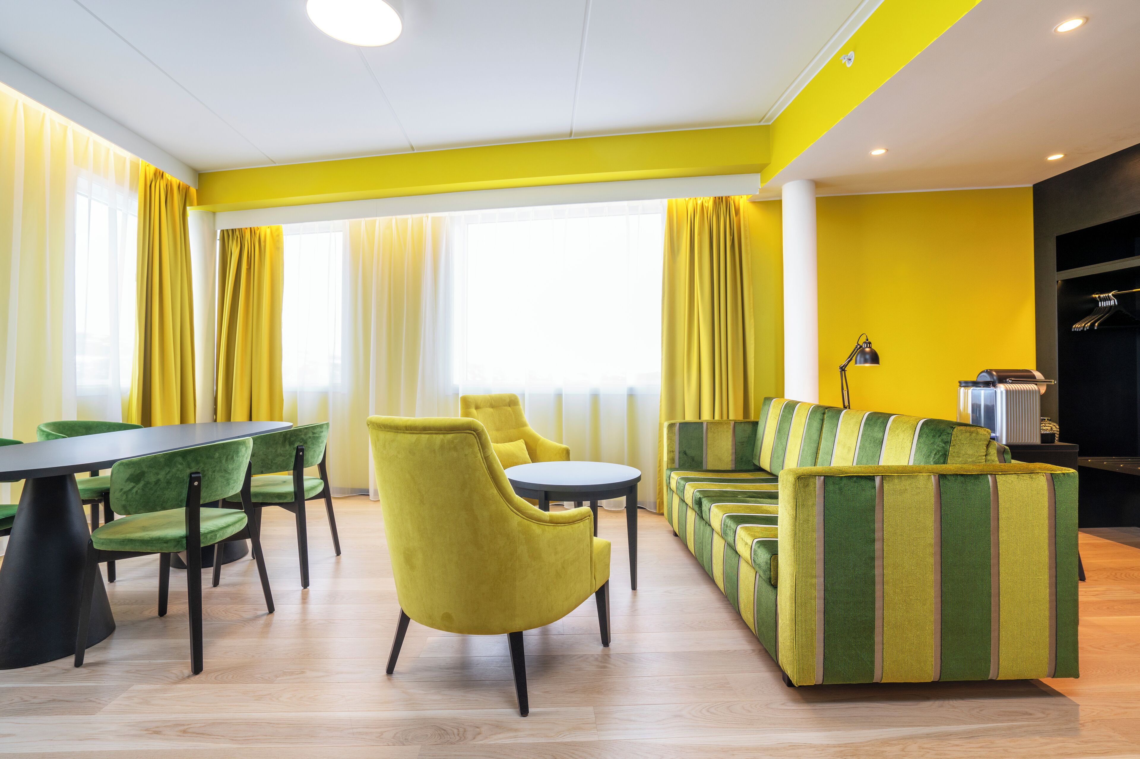 Ein modernes Zimmer mit Essbereich, gelben Vorhängen und einem Sofa mit gestreiften Kissen.