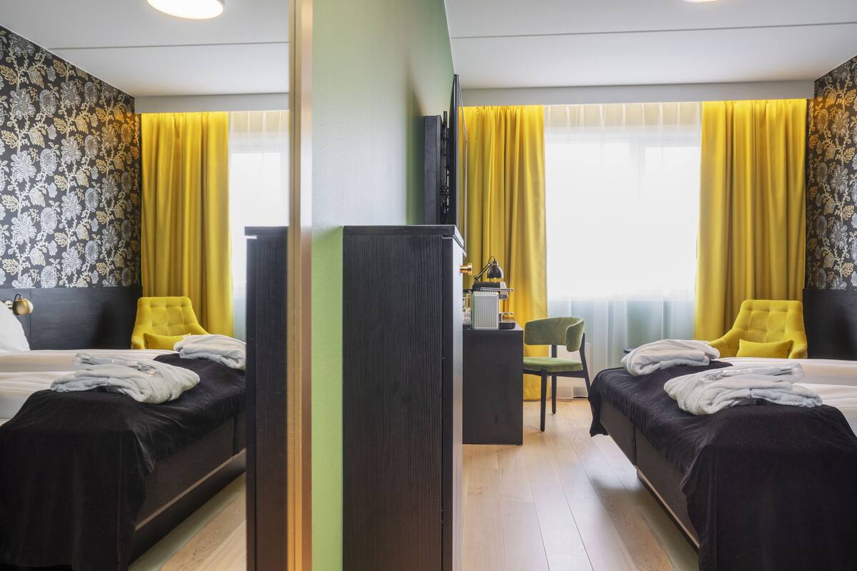 Habitación de hotel con dos camas, un escritorio y una silla.