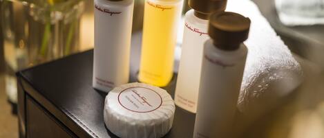 A selection of skincare products on a table, including a white round container labeled "Tuscany Soak" and three bottles with brown caps.