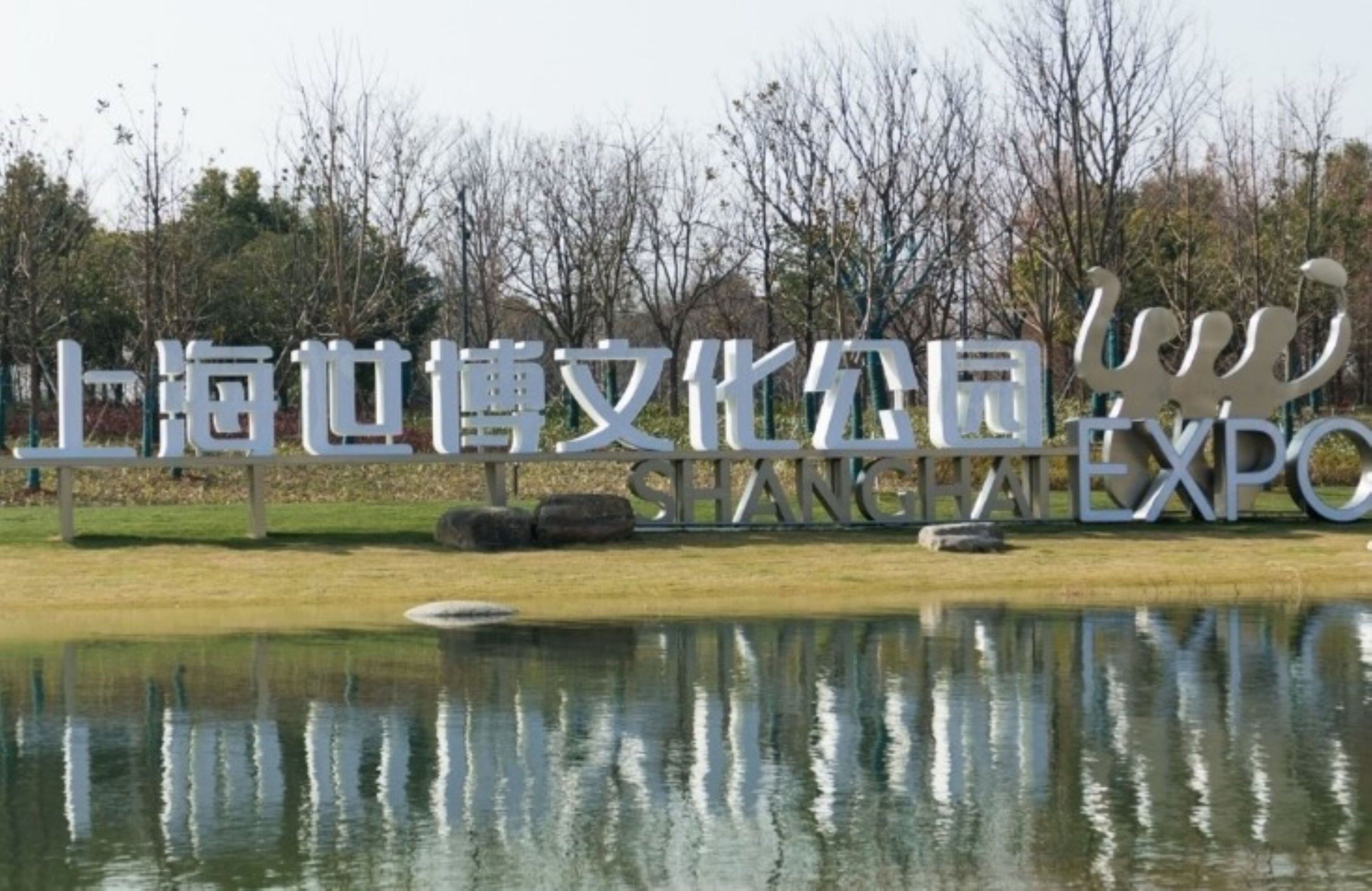 A sign with the text "Shanghai Expo" and a reflection in the water.