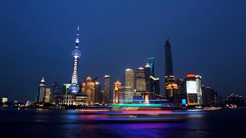 A nighttime city skyline with illuminated buildings and a body of water reflecting lights.