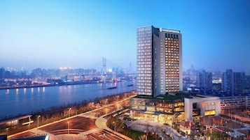 Un hotel moderno e imponente, con un grande cartello InterContinental, affacciato su un fiume e con un ponte sullo sfondo.
