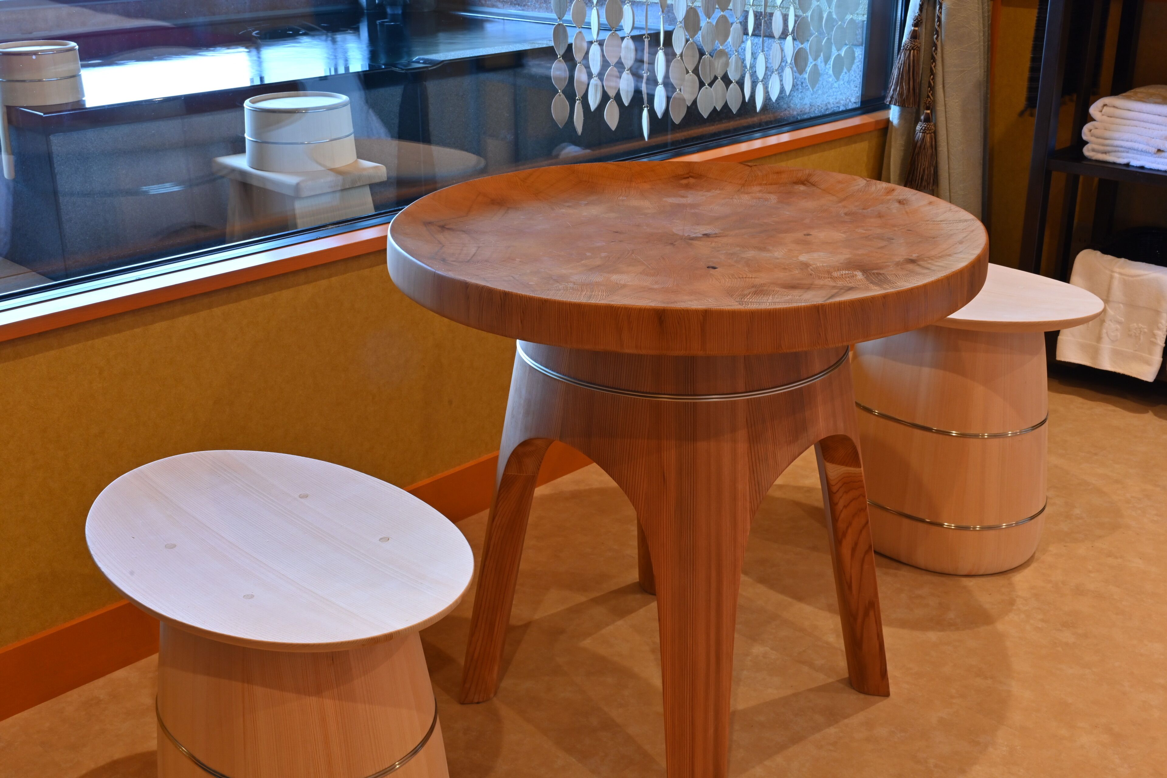 A wooden table and stool set in a room with a glass partition and a window.