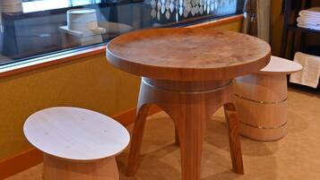 A wooden table and stool set in a room with a glass partition and a window.