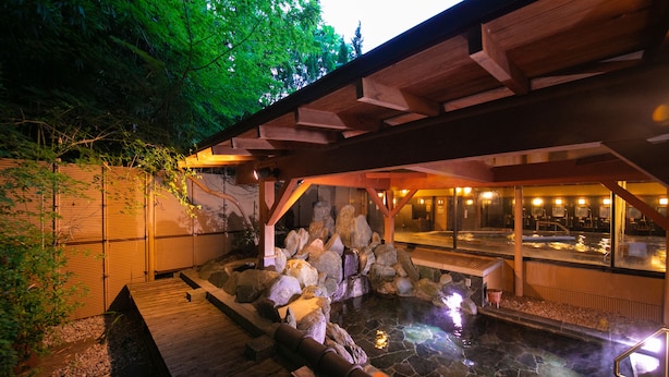 A hot spring area with wooden walkways, rocks, and a stone pool. - Biwako Hanakaido (Otsu)