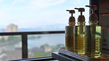Three bottles of liquid on a tray by a window overlooking a river.