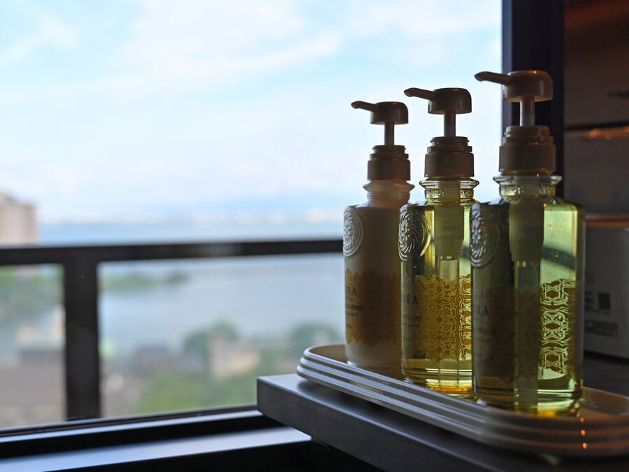 Three bottles of liquid on a tray by a window overlooking a river.