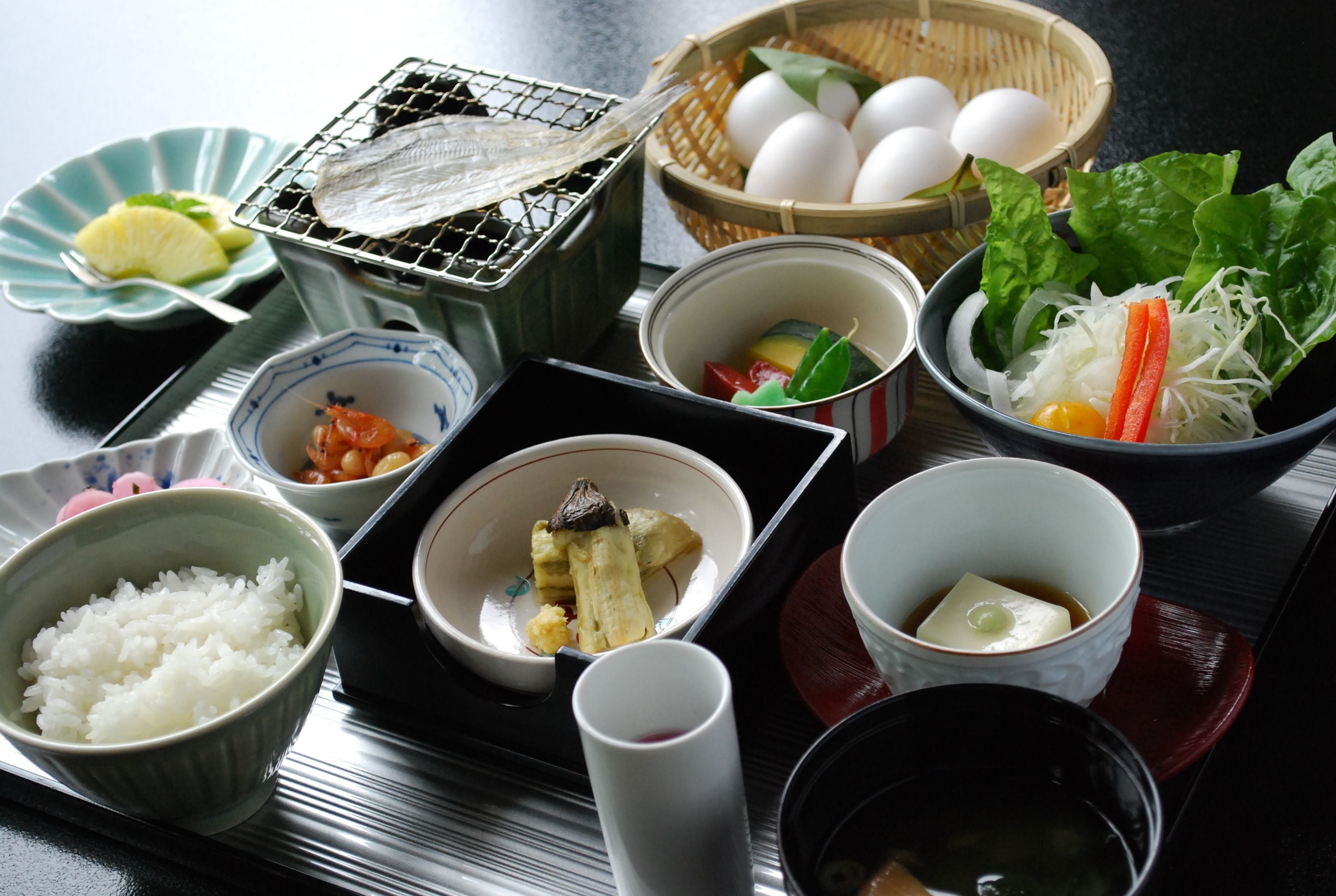 A variety of dishes including rice, eggs, and vegetables on a tray.