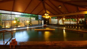 An indoor swimming pool with wooden benches and a view of the outside. - Biwako Hanakaido (Otsu)