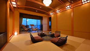 A traditional Japanese-style room with tatami flooring, a low table with cushions, and a view of the sea through large windows. - Biwako Hanakaido (Otsu)