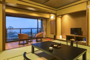 Habitación de hotel con un ventanal grande, televisión, una mesa de comedor y dos sillas.