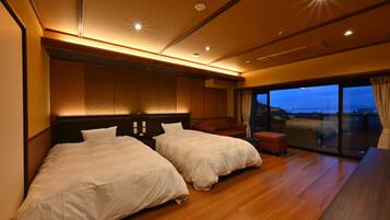 A hotel room with two beds, a wooden floor, a large window with a view, and a balcony.