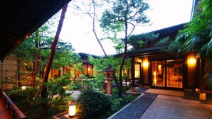 A traditional Japanese-style garden with a pathway leading to a building with a wooden exterior and a tiled entrance. - Biwako Hanakaido (Otsu)