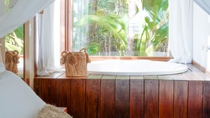 A bedroom with a wooden floor, a large window with sheer curtains, a bed with white linens, and a woven basket on the windowsill. - Vila dos Orixás Boutique Hotel (Cairu)