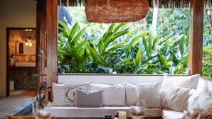 A cozy seating area with a sofa, cushions, and a table with glasses and a candle. - Vila dos Orixás Boutique Hotel (Cairu)