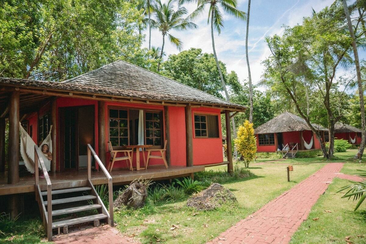 A red building with a porch, wooden steps, and a hammock.