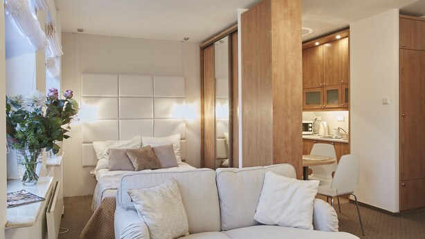 A modern hotel room with a large bed, a sofa, a dining area, and a kitchen. - Warsaw Apartments Magnolie (Warsaw)