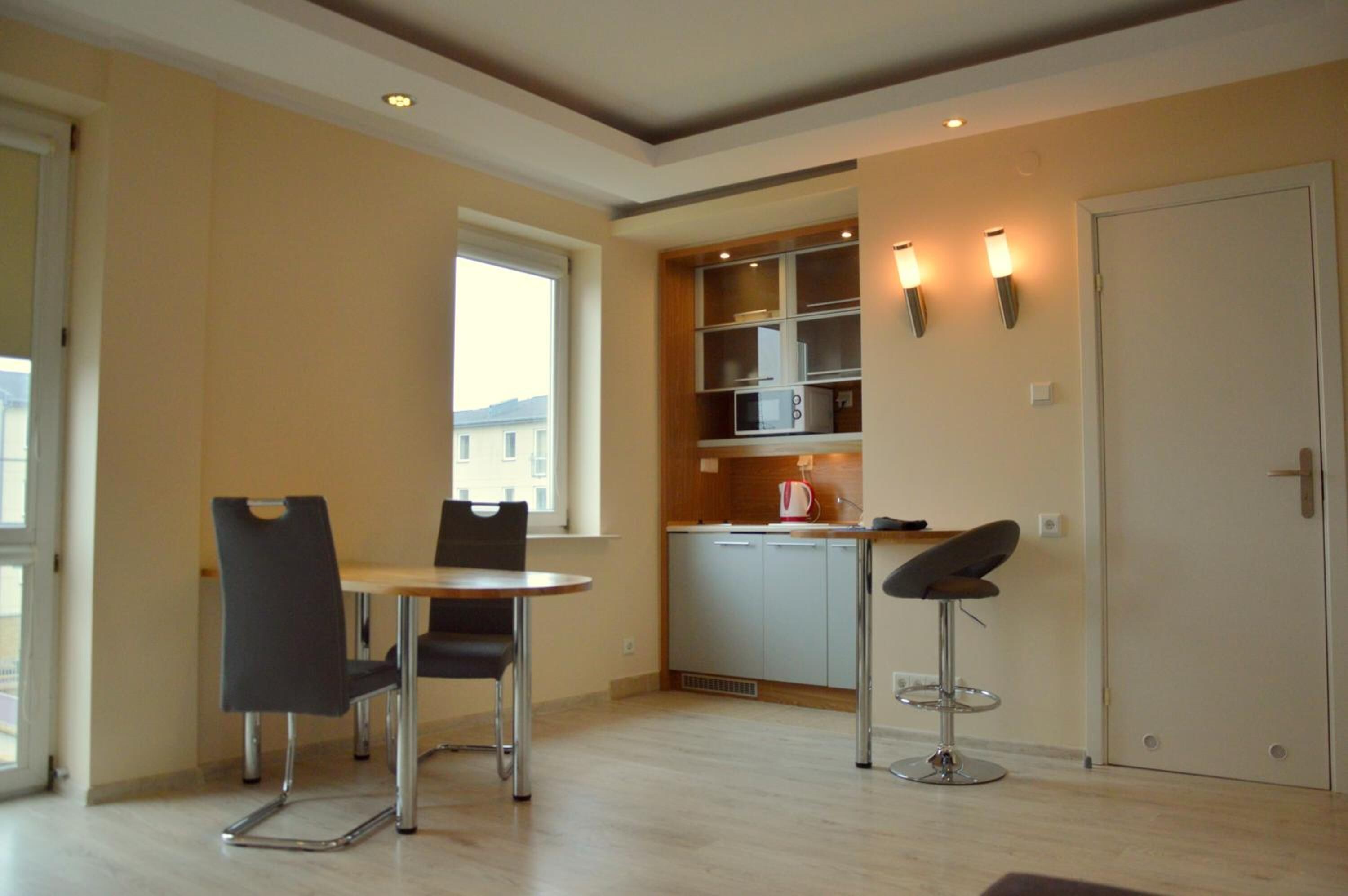 A modern kitchen with built-in appliances, a dining area with two chairs, and a bar stool.